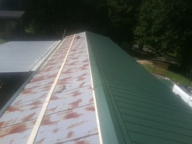 Old rusted panels beside newly installed green metal roofing — Wind Damage Roof Repair by Roofing Brothers in Shaftsbury