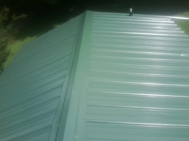 New green metal panels meeting at the ridge of a roof — Flat Roof Repair work by our crew in Shaftsbury