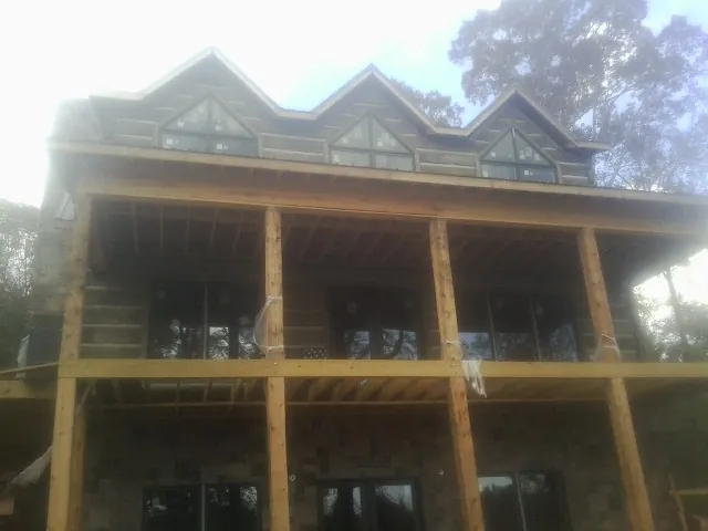Dormers and porch framing on a large log home under construction — Roof Coating work by our crew in Shaftsbury