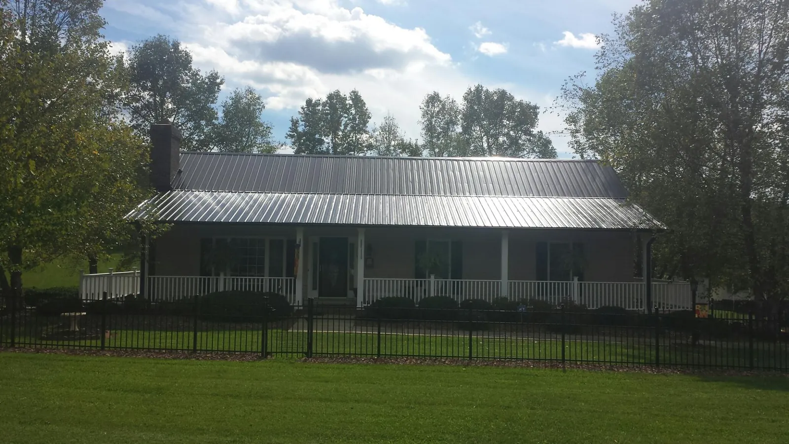 Gray metal roof on a brick ranch with a full width front porch — Gutter Guard Installation work by our crew in Shaftsbury