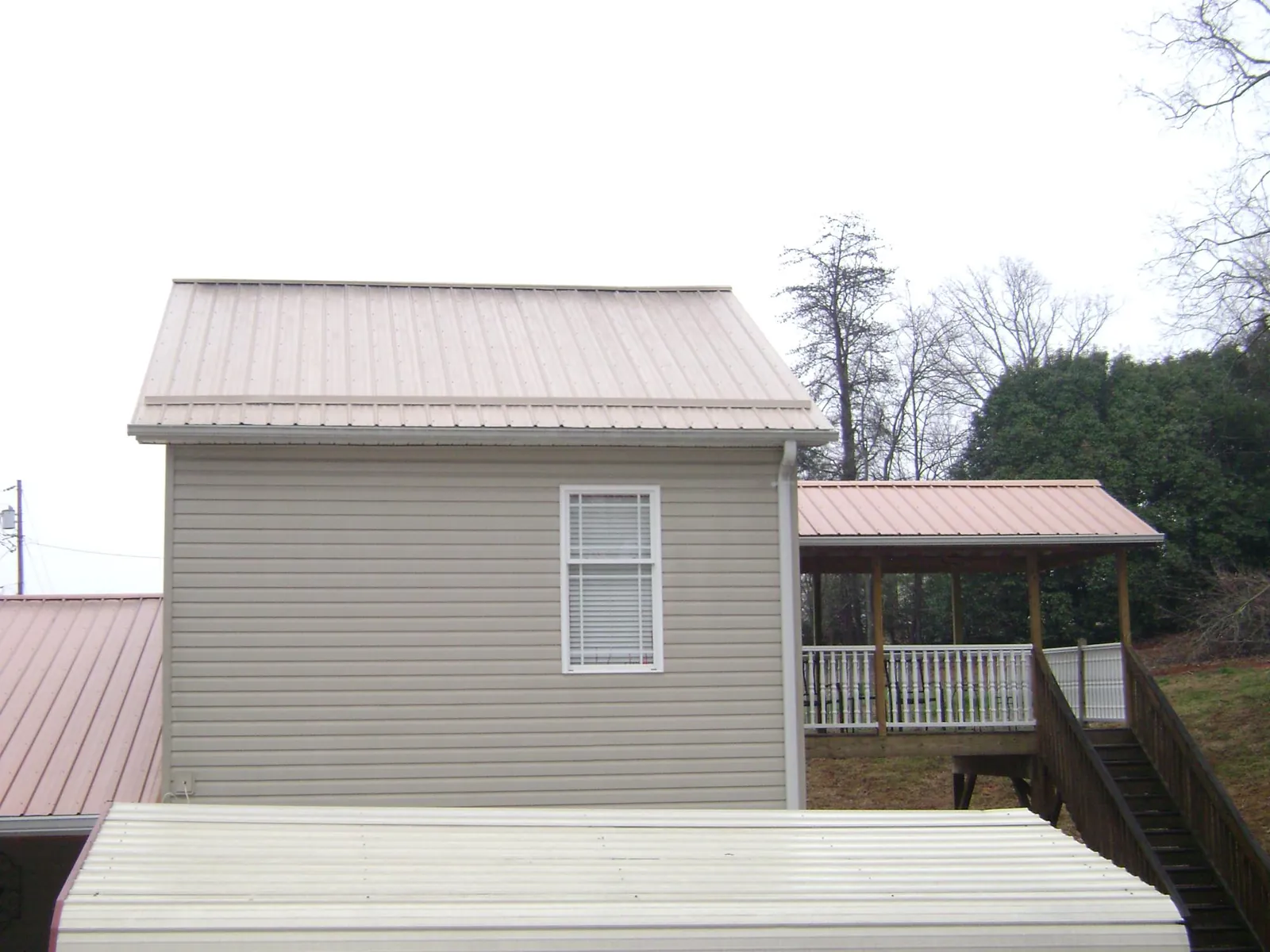 Tan metal roofs on a two story addition and attached porch, from a Roof Replacement job in Shaftsbury