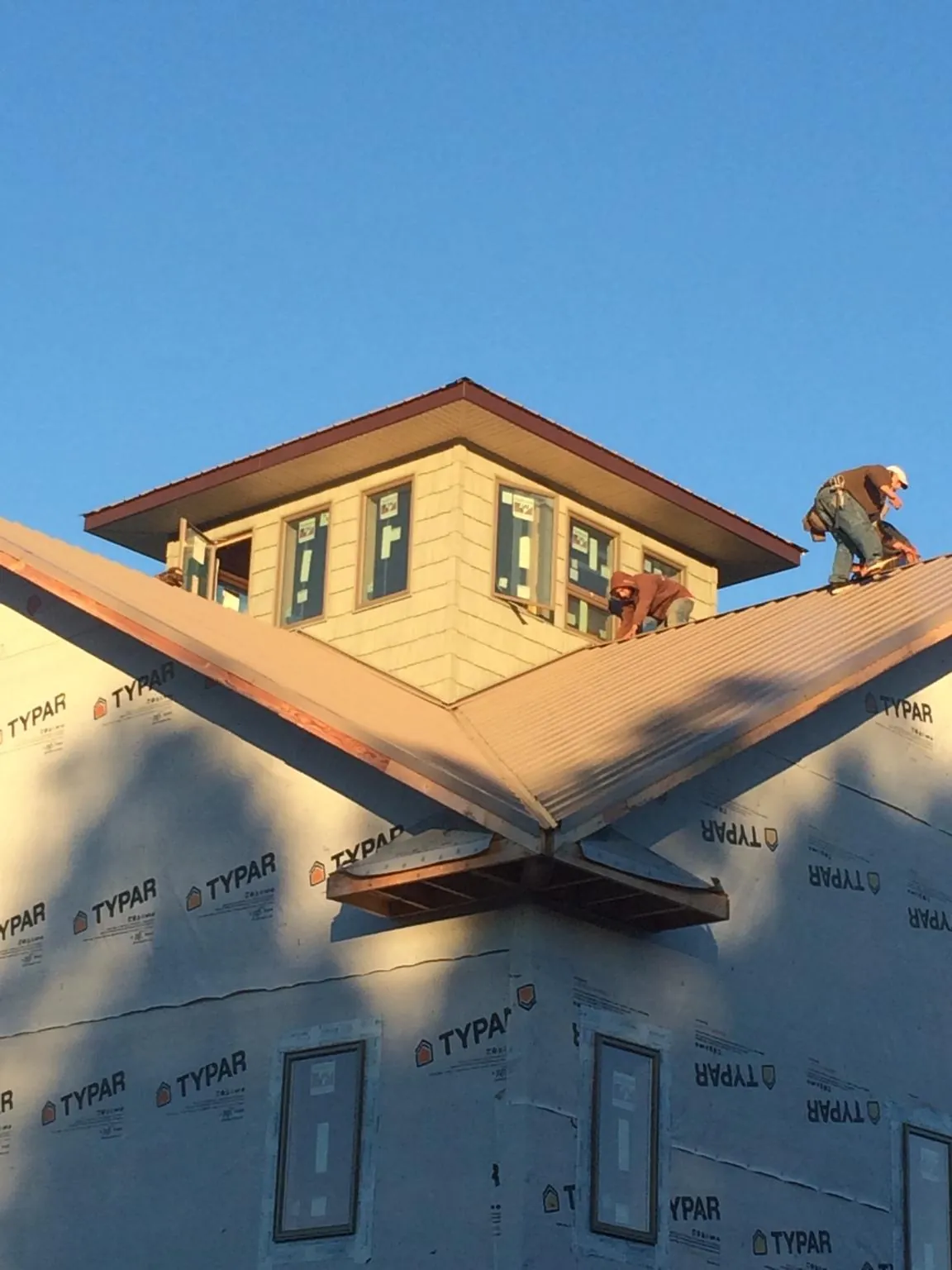 Roofers working around a rooftop cupola on a new metal roof at sunset — Roof Waterproofing in Shaftsbury by Roofing Brothers